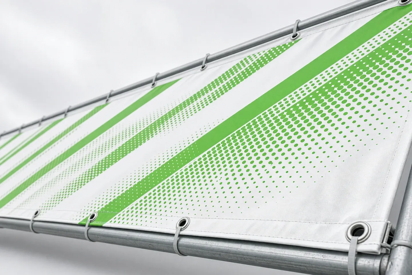 Gespanntes PVC-Banner mit grünem Muster, Ösen und Saum an einem Bauzaun befestigt